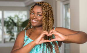 African american woman at home smiling in love showing heart symbol and shape with hands. Romantic concept.